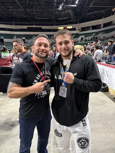 Frankie Edgar with a student in a gi at a jiu-jitsu tournament